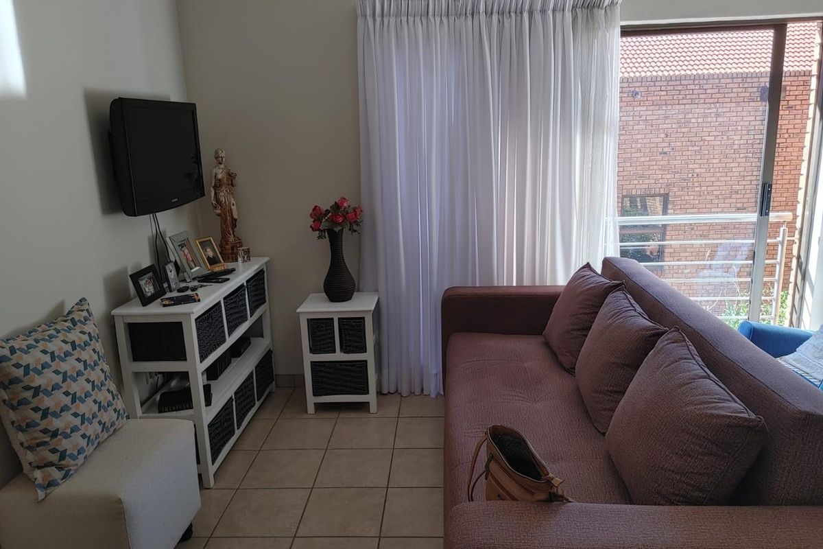 A compact living room featuring tiled flooring and a sliding glass door that provides access to an outdoor balcony area.