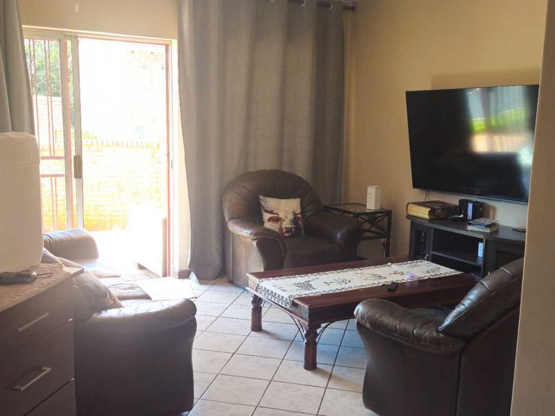 A living room featuring tiled flooring and a sliding glass door providing access to the exterior.
