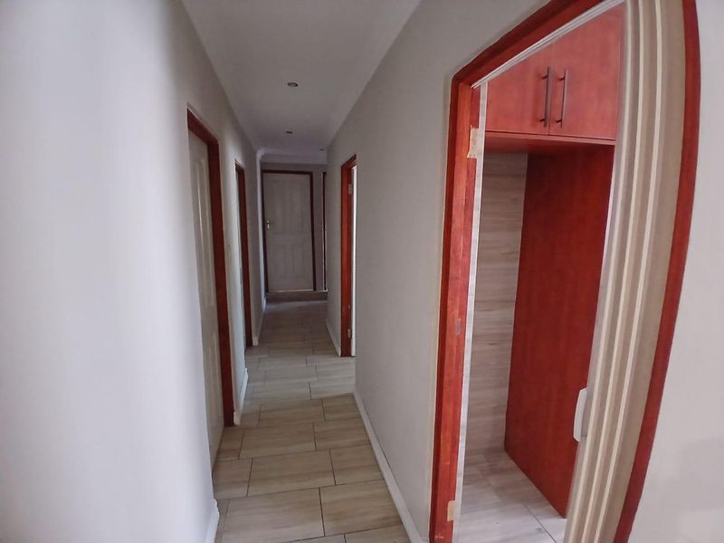 A clean, tiled hallway featuring built-in storage cabinetry and multiple doorways leading to adjacent rooms.