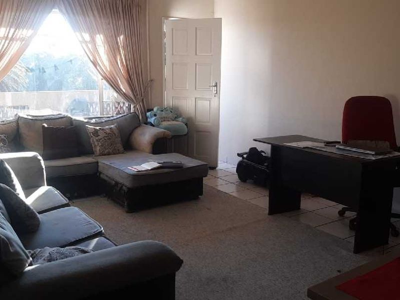 A spacious living area featuring tiled flooring, a large window with natural light, and direct access to an exterior door.