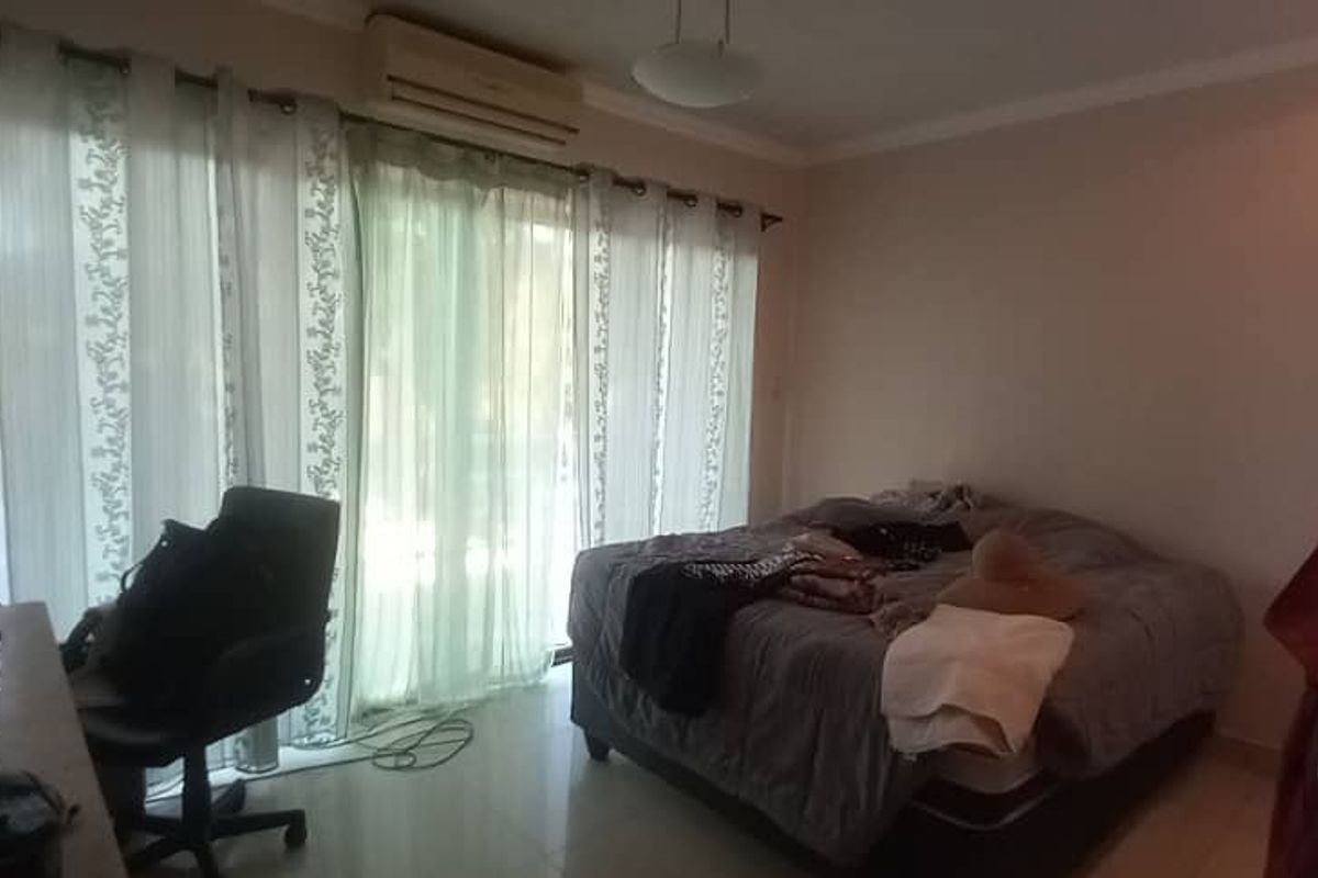 A bedroom featuring tiled flooring, a wall-mounted air conditioning unit, and large sliding glass doors providing access to the exterior.