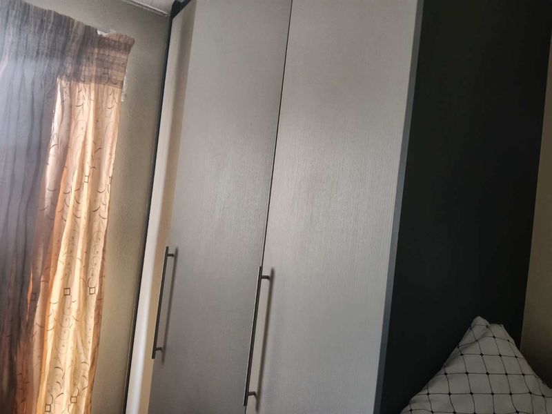 A bedroom featuring a built-in wardrobe with modern handles and neutral cabinetry finishes.