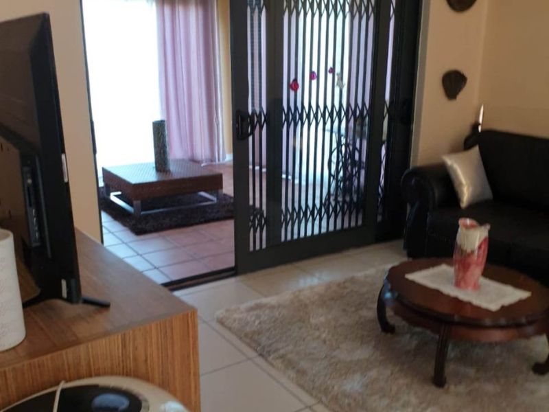 Living room featuring tiled flooring and a sliding glass door with a security gate leading to an outdoor patio area.