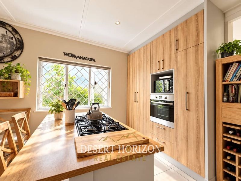 Modern kitchen featuring wood-look cabinetry, a central island with a built-in gas hob, and integrated oven and microwave appliances.