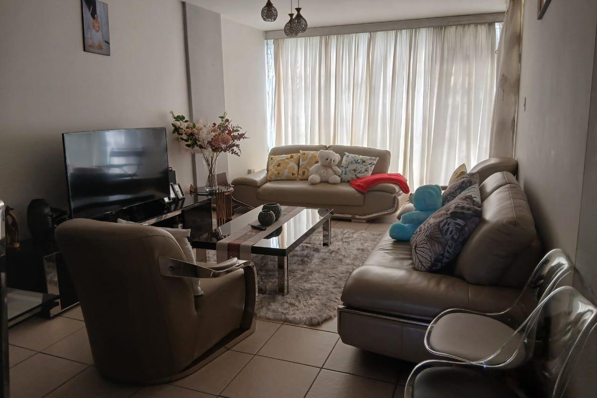 A comfortable living room featuring tiled flooring and large windows, providing a bright and functional space for relaxation.