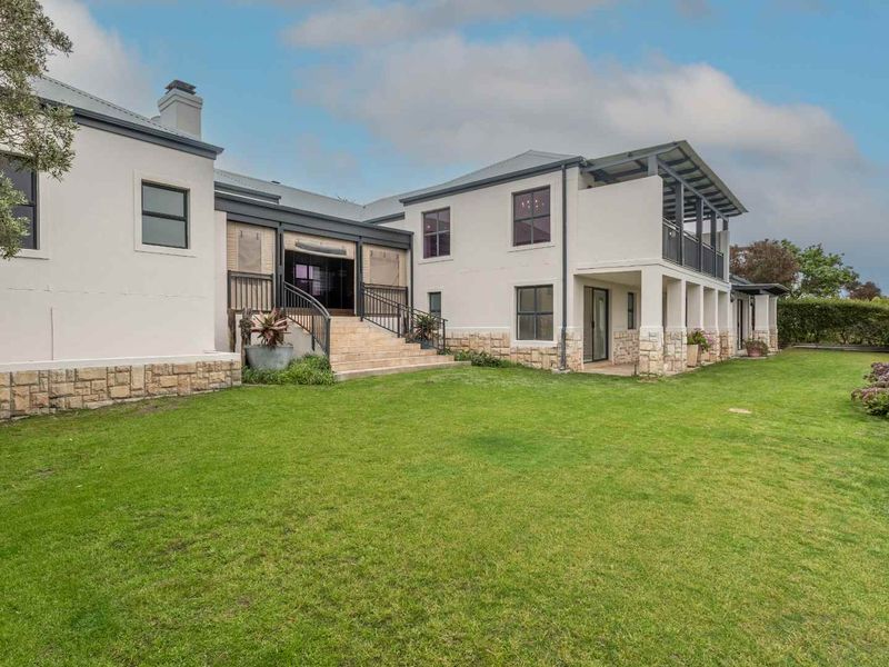Spacious rear elevation featuring stone cladding, a landscaped garden, and an elevated balcony area, showcasing well-maintained architectural finishes.