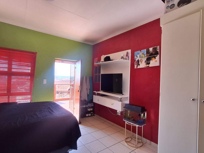 A bedroom featuring tiled flooring, a built-in wardrobe, and direct access to an outdoor balcony through a security gate.
