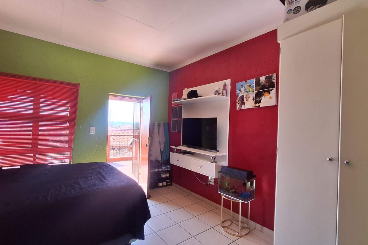 A bedroom featuring tiled flooring, a built-in wardrobe, and direct access to an outdoor balcony through a security gate.