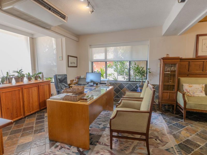 A functional home office featuring slate tile flooring, built-in cabinetry, and a wall-mounted air conditioning unit with ample natural light.