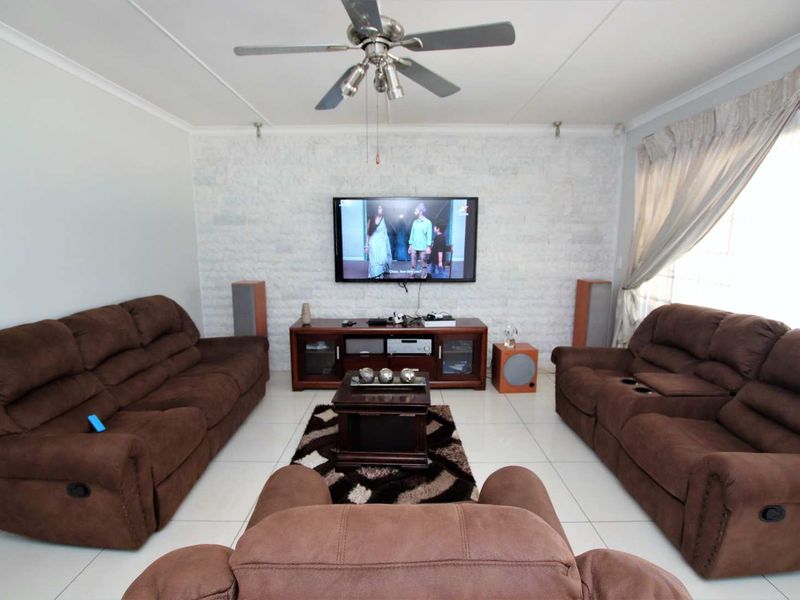 A comfortable living room featuring a textured stone accent wall, tiled flooring, and a ceiling fan, creating a functional and inviting space.