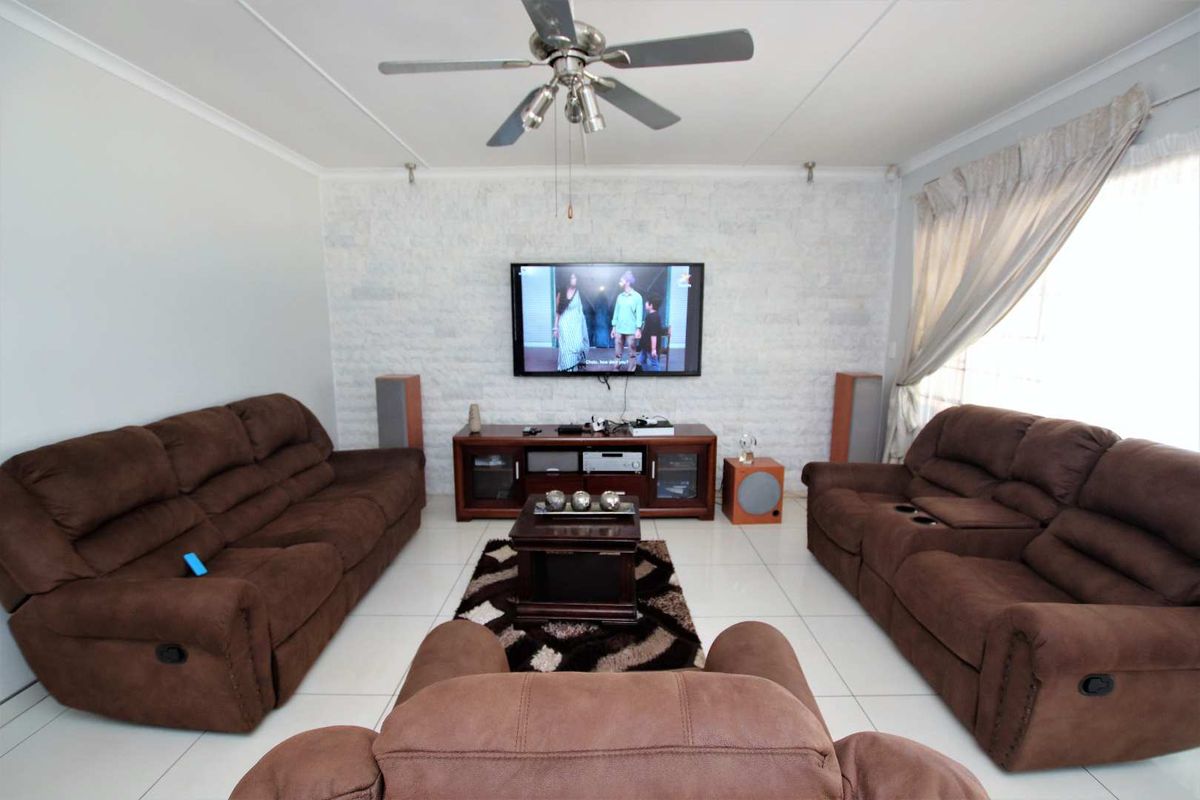 A comfortable living room featuring a textured stone accent wall, tiled flooring, and a ceiling fan, creating a functional and inviting space.