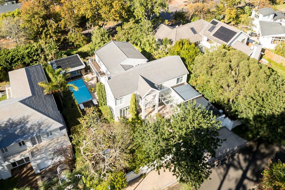 Aerial view of a residential property featuring a swimming pool, tiled roof with solar panels, and a landscaped garden setting.