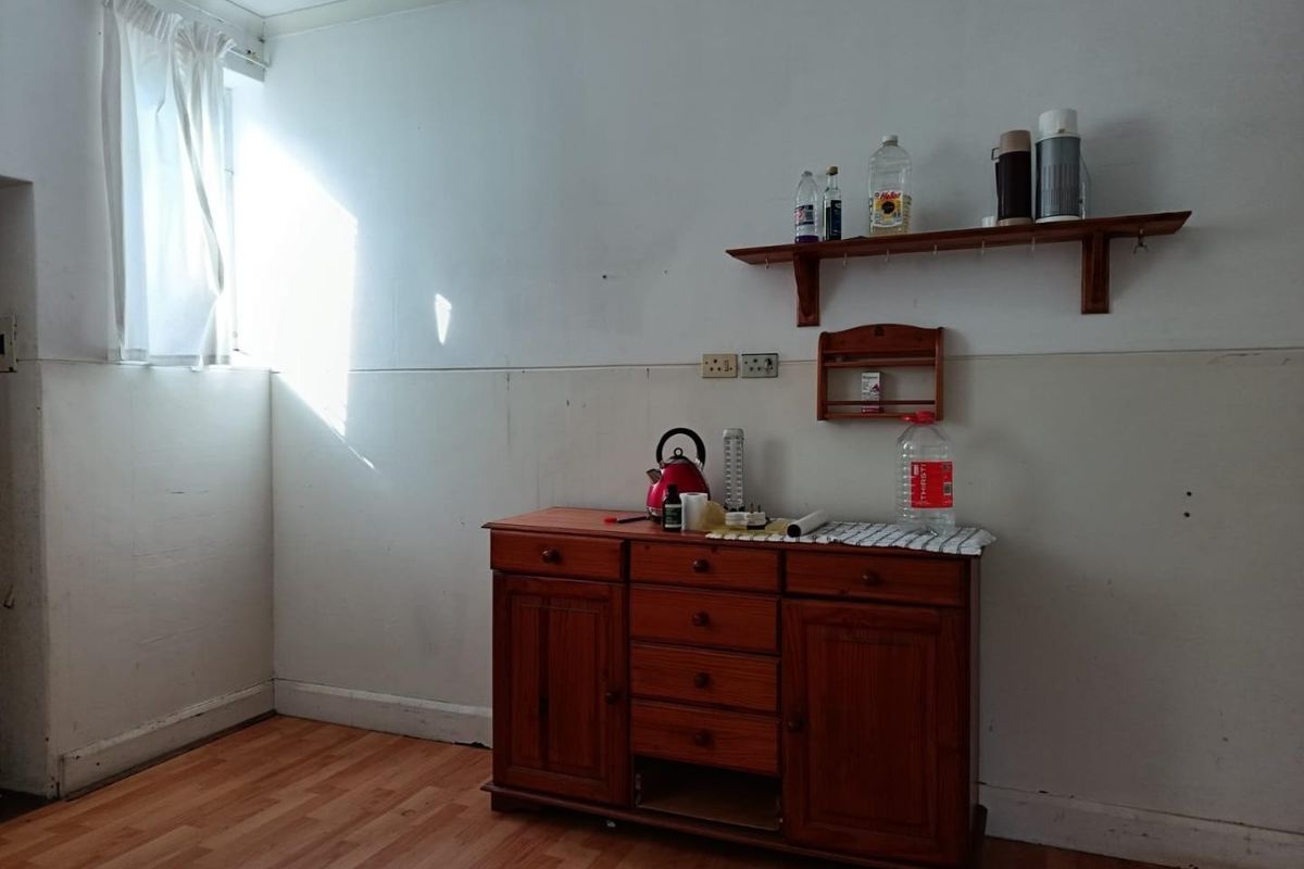 A simple kitchen area featuring laminate flooring and wall-mounted shelving, offering a blank canvas for potential renovation and modernization.
