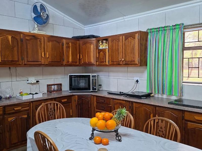 A kitchen featuring wooden cabinetry, tiled walls, and laminate countertops, with a dining area integrated into the space.