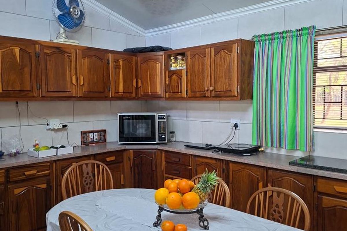 A kitchen featuring wooden cabinetry, tiled walls, and laminate countertops, with a dining area integrated into the space.