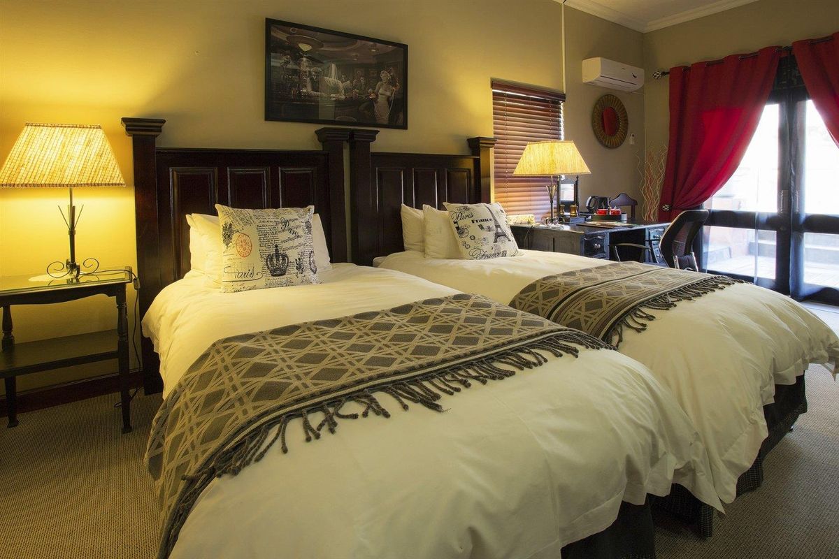 A well-maintained guest bedroom featuring twin beds, carpeted flooring, a wall-mounted air conditioning unit, and direct access to an outdoor area via sliding glass doors.
