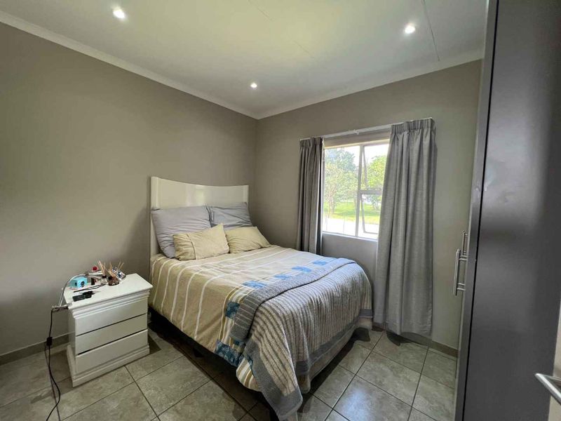 A well-maintained bedroom featuring neutral wall tones, tiled flooring, recessed downlighting, and a built-in cupboard for storage.