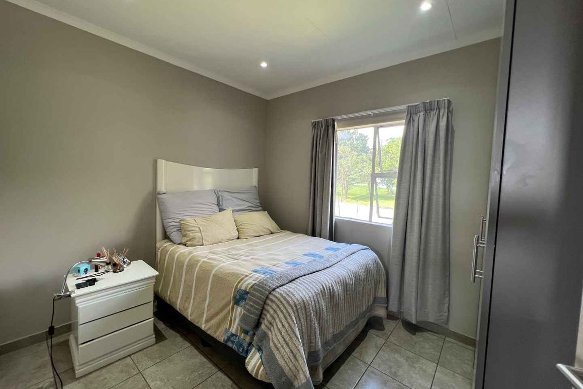 A well-maintained bedroom featuring neutral wall tones, tiled flooring, recessed downlighting, and a built-in cupboard for storage.