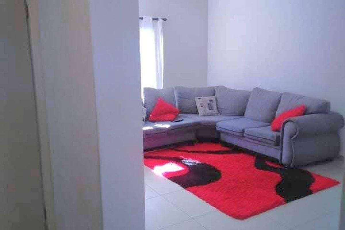 A view into a living room area featuring neutral tiled flooring and a simple ceiling light fixture.