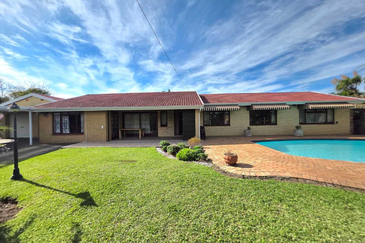 Rear view of the house featuring a swimming pool, paved patio area, and a well-maintained lawn.