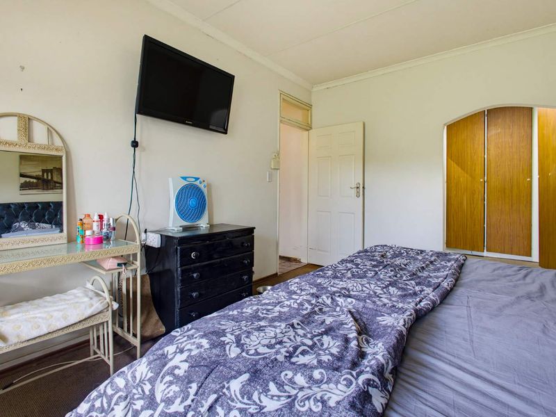 A bedroom featuring built-in wooden cupboards and carpeted flooring, requiring cosmetic updates to improve its overall appeal and condition.