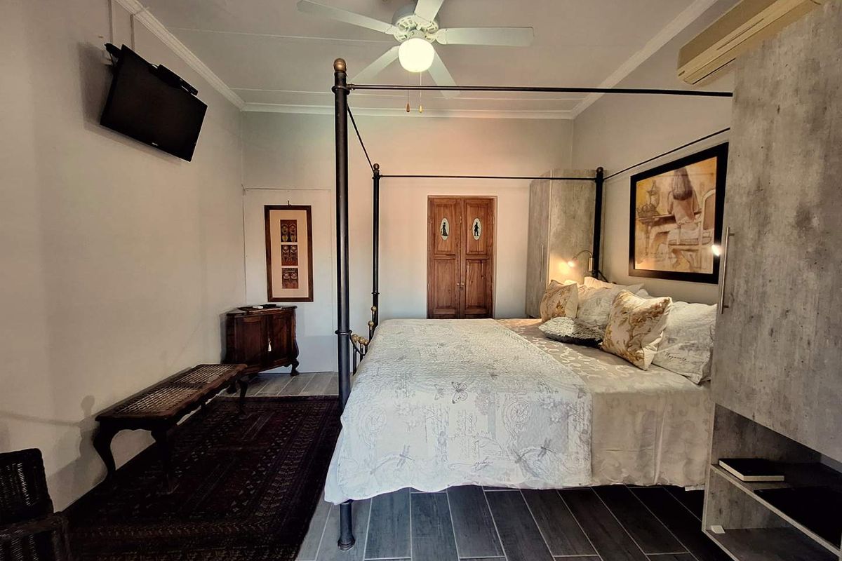 A well-maintained bedroom featuring a ceiling fan, split-system air conditioning, and tiled flooring with built-in storage.