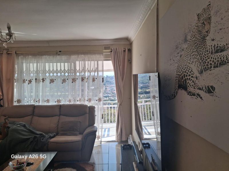 Living room featuring tiled floors, decorative ceiling cornices, and a sliding glass door providing access to a balcony with scenic views.