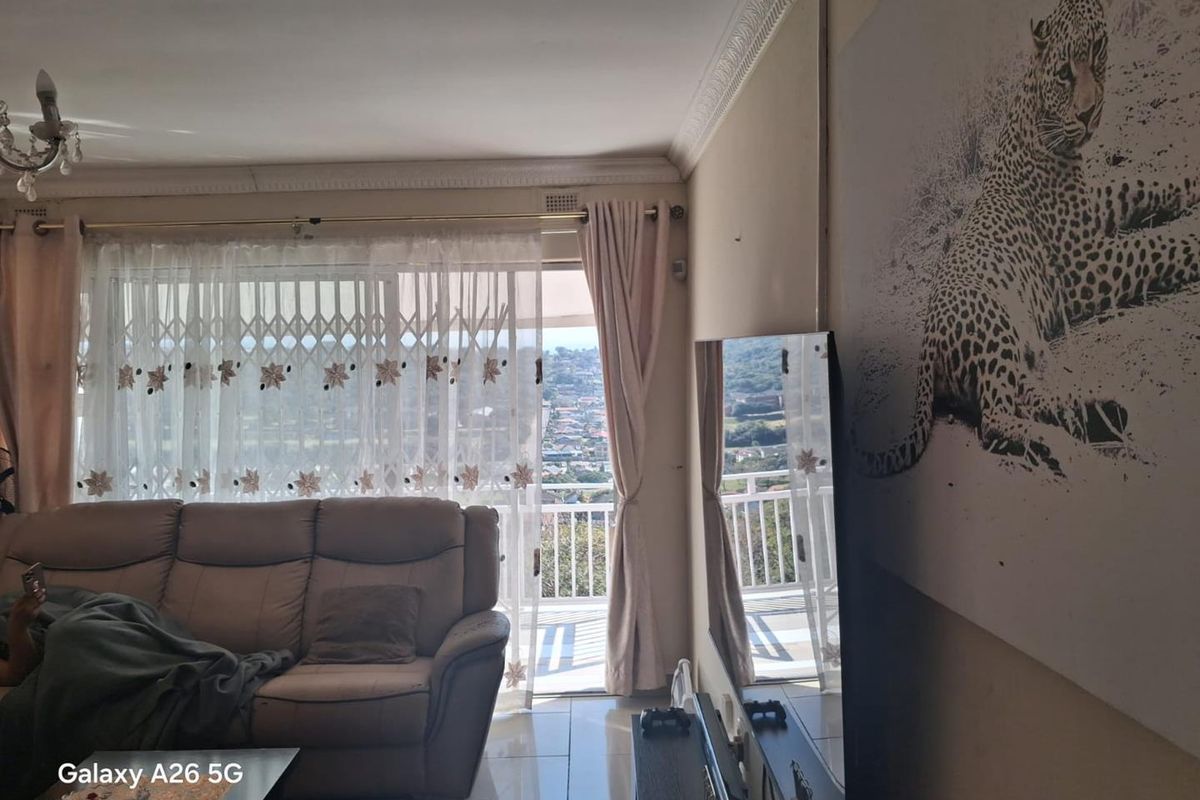 Living room featuring tiled floors, decorative ceiling cornices, and a sliding glass door providing access to a balcony with scenic views.