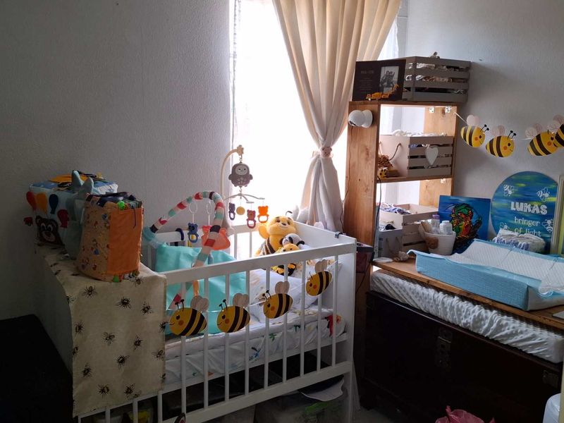 A cozy bedroom space featuring a window with curtains, suitable for a nursery or child's room.
