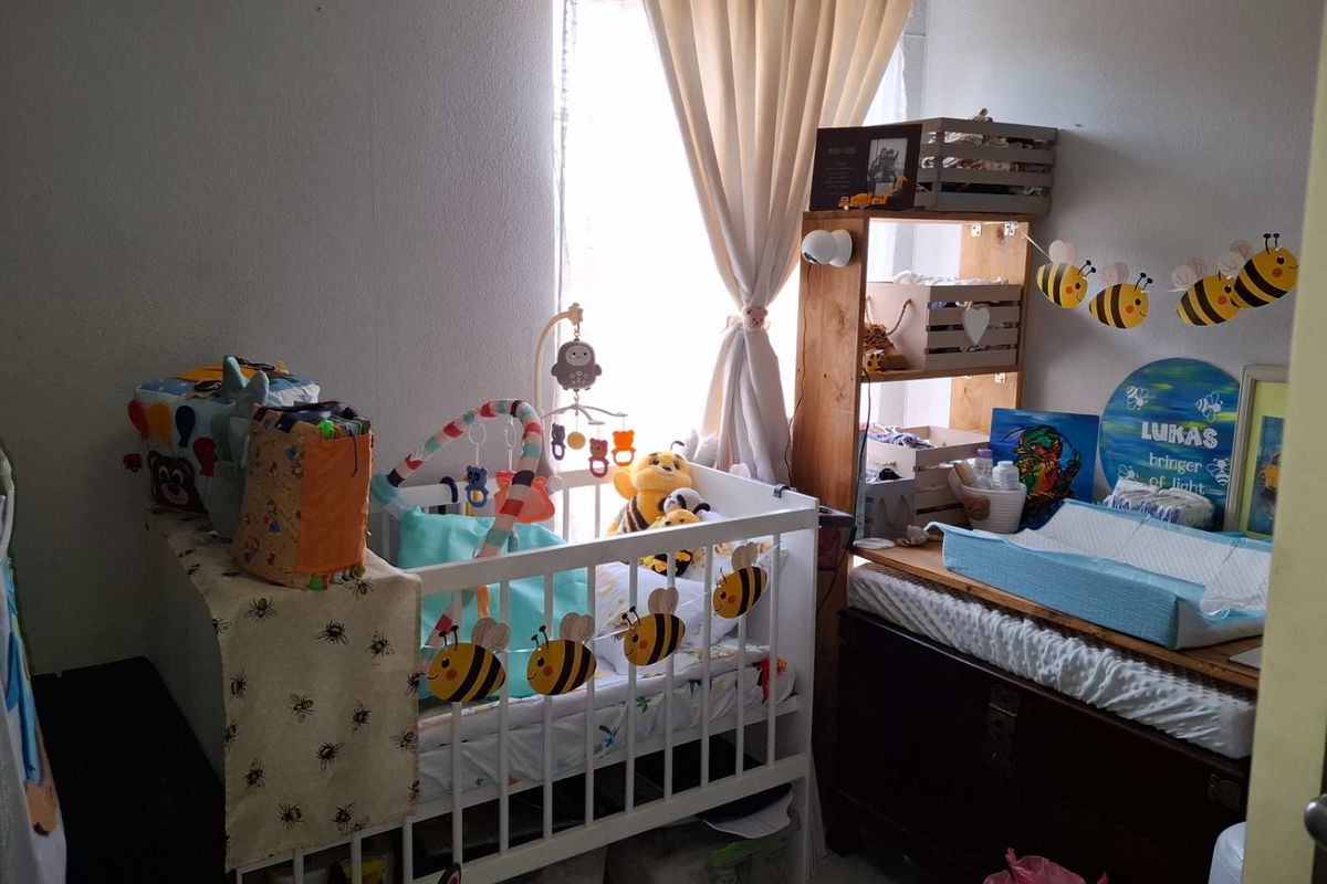 A cozy bedroom space featuring a window with curtains, suitable for a nursery or child's room.
