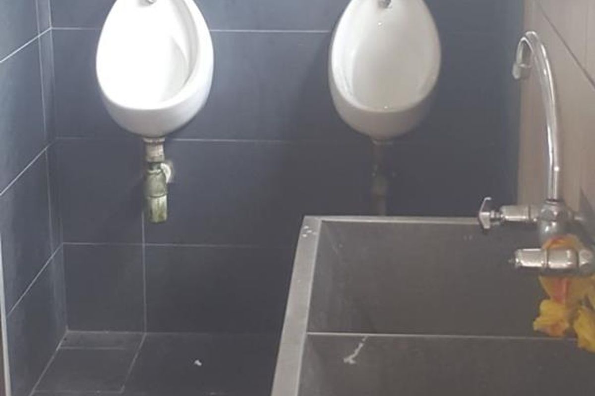Industrial restroom facility featuring two wall-mounted ceramic urinals and a stainless steel double-basin utility sink with chrome faucets.