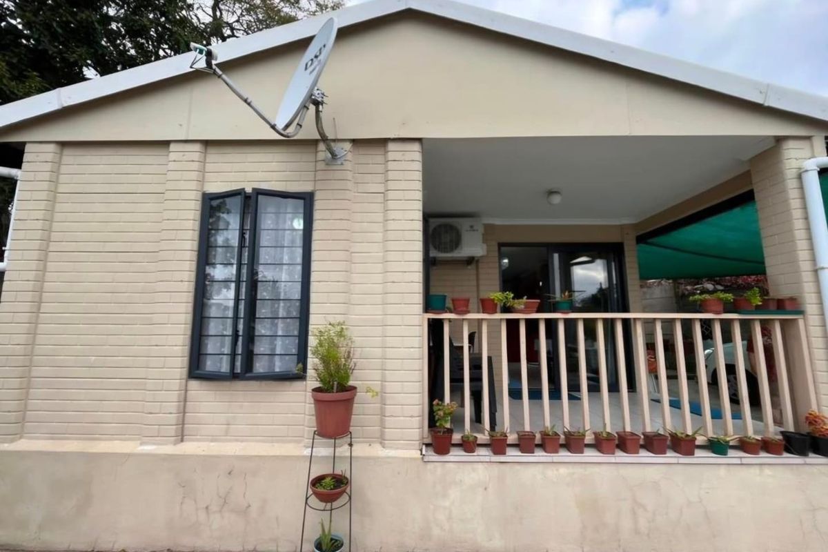 Rear exterior view of the house featuring a covered patio area, security-fitted windows, and an external air conditioning unit.
