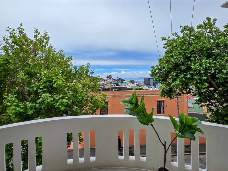 A private balcony featuring a white balustrade with an elevated view overlooking the surrounding neighborhood and urban landscape.