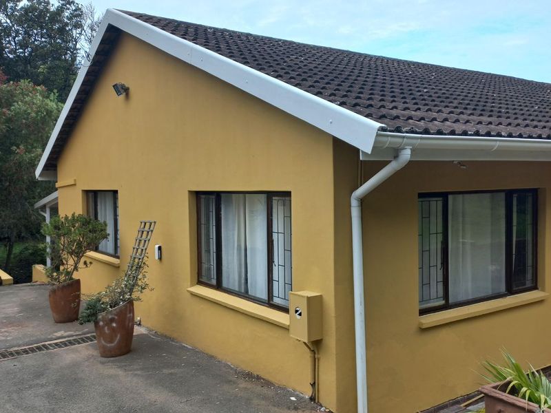 Side and rear view of the property featuring a tiled roof, guttering system, and security bars on the windows.