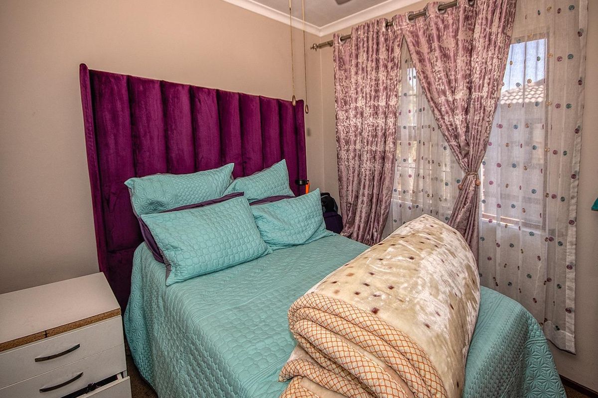 A bedroom featuring a ceiling fan and window with curtain tracks.