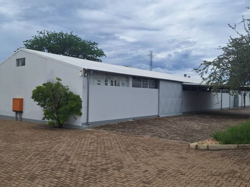 Exterior view of an industrial warehouse building featuring a paved driveway, metal roofing, and large sliding access doors.