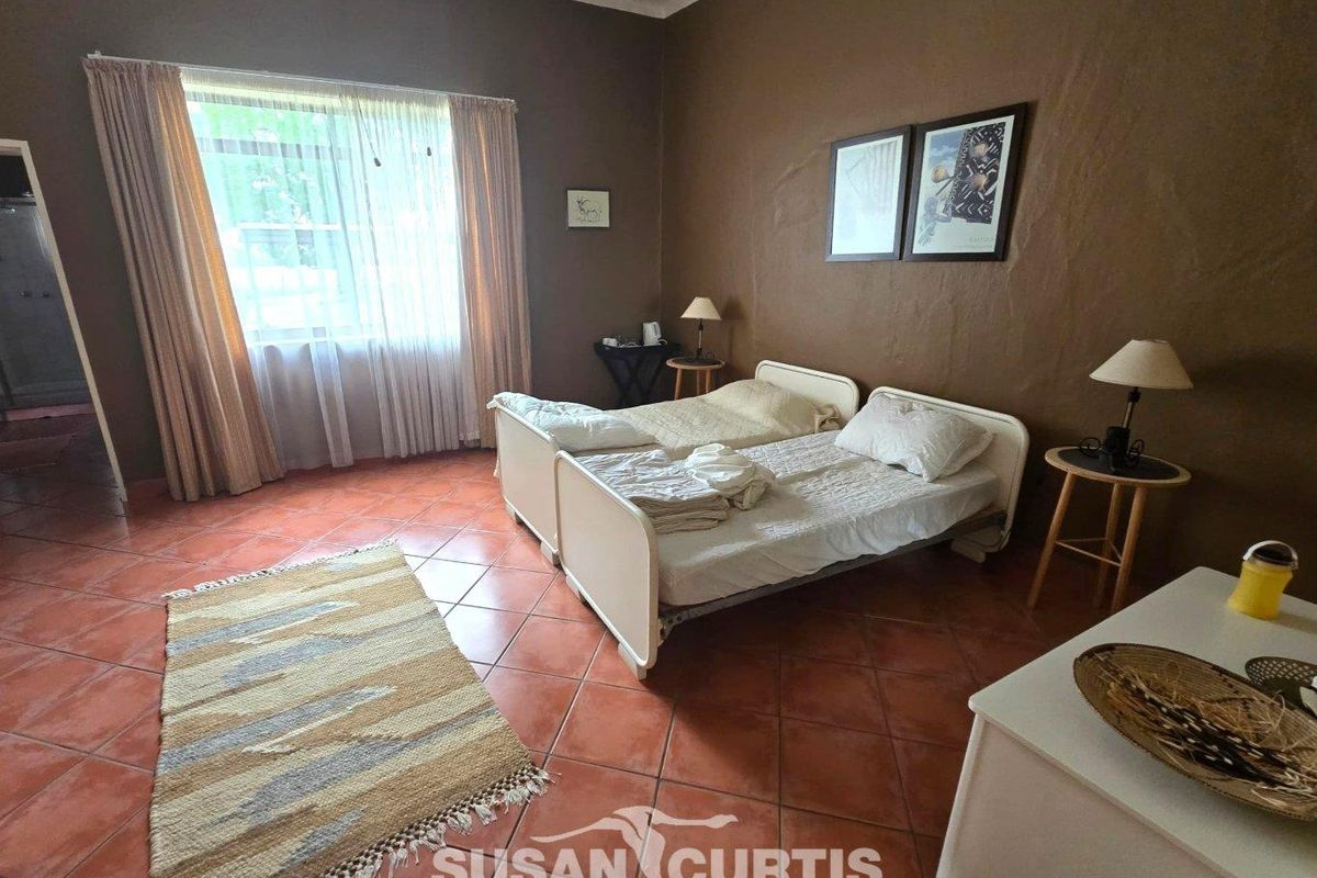 A spacious bedroom featuring terracotta floor tiles and neutral wall finishes, offering a comfortable and functional living space.