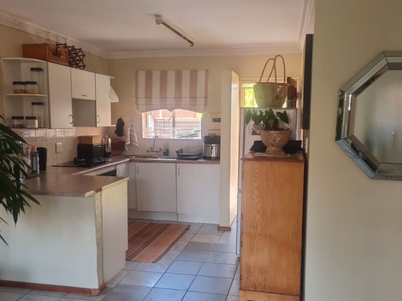 Functional kitchen featuring white cabinetry, laminate countertops, and tiled flooring, offering a practical layout with integrated hob and sink area.