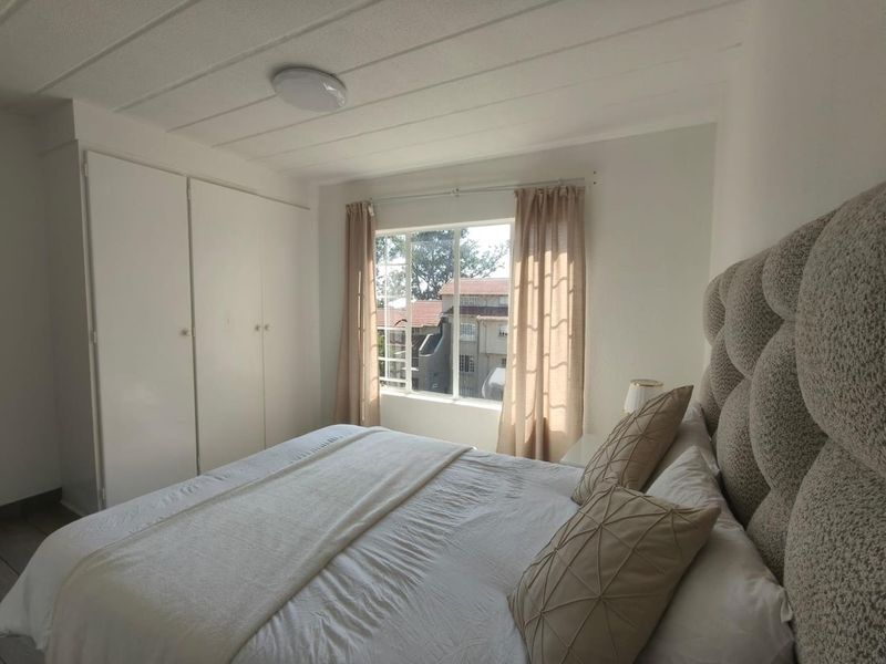 A bright bedroom featuring built-in cupboards and a window with natural light, offering a comfortable and functional living space.