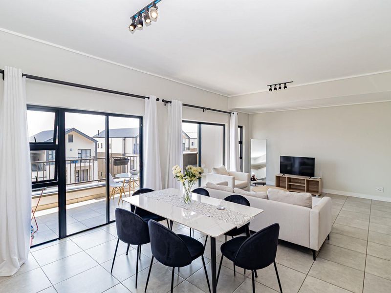 Spacious open-plan living and dining area featuring large sliding glass doors that provide abundant natural light and direct access to the balcony.