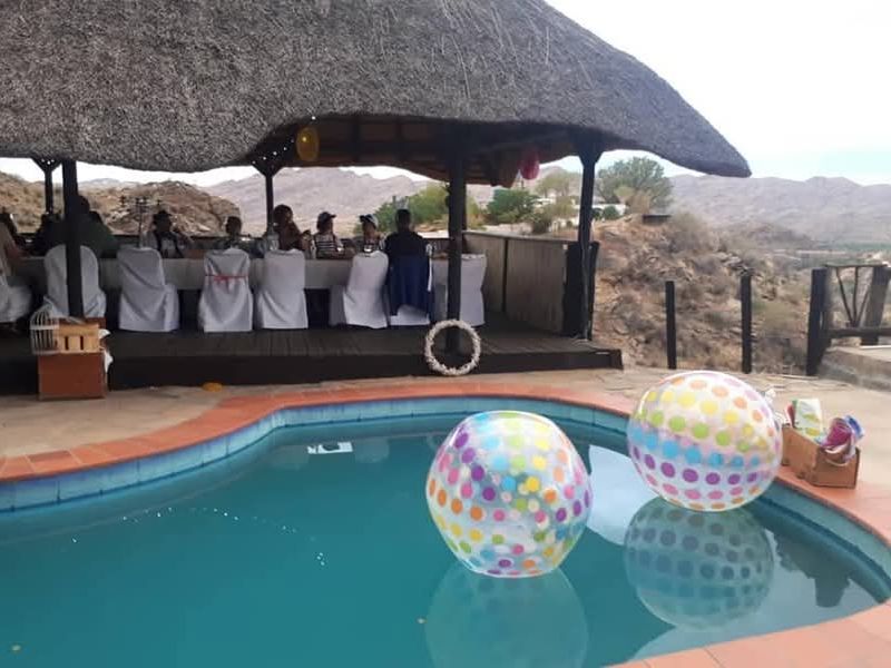 Outdoor pool area featuring a thatched lapa with timber decking, overlooking a scenic landscape, perfect for outdoor entertainment.
