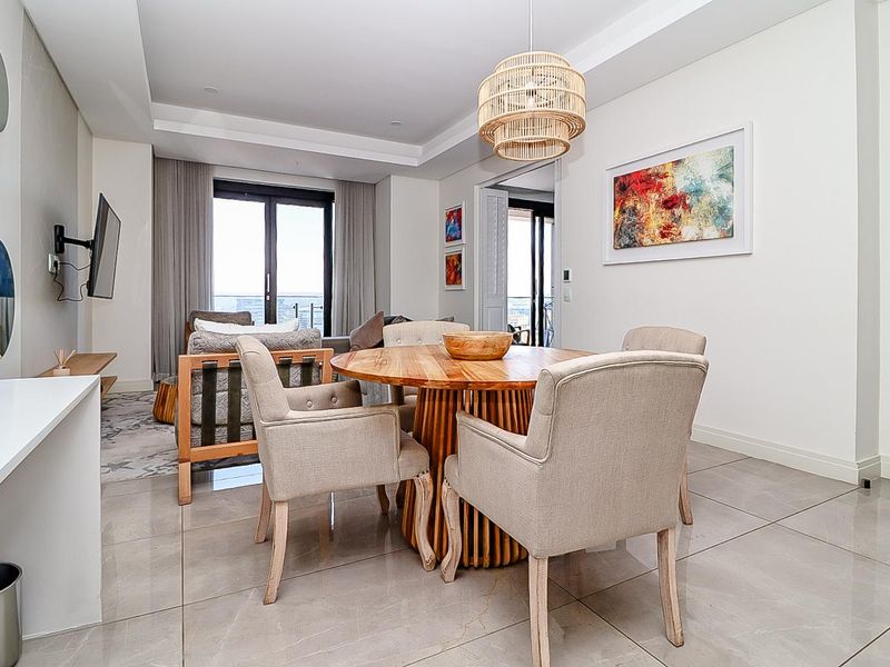 Modern open-plan living and dining area featuring sleek porcelain floor tiles, recessed ceiling details, and large sliding doors leading to a balcony.