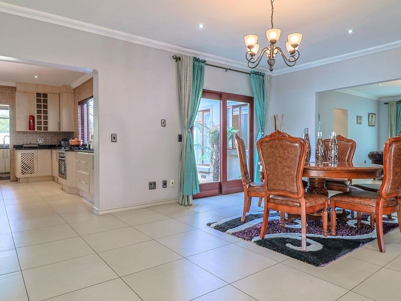 Spacious open-plan living and dining area featuring tiled floors, recessed lighting, and seamless flow into a well-equipped kitchen with granite countertops.