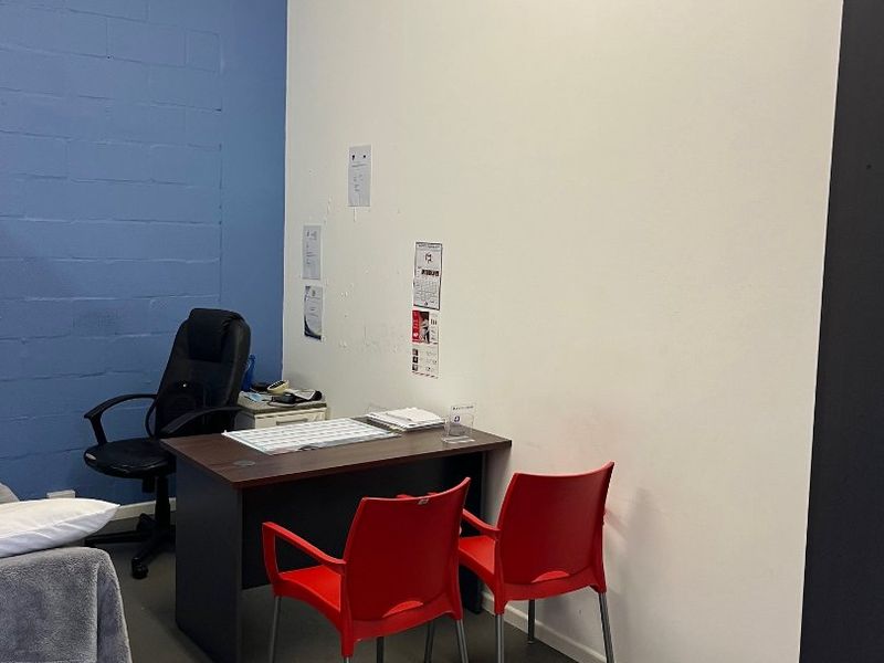A functional office space featuring painted concrete block walls and concrete flooring, suitable for a professional workspace or consultation room.