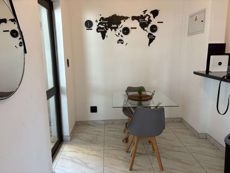 A compact dining area featuring modern marble-look floor tiles and a sliding glass door providing natural light.