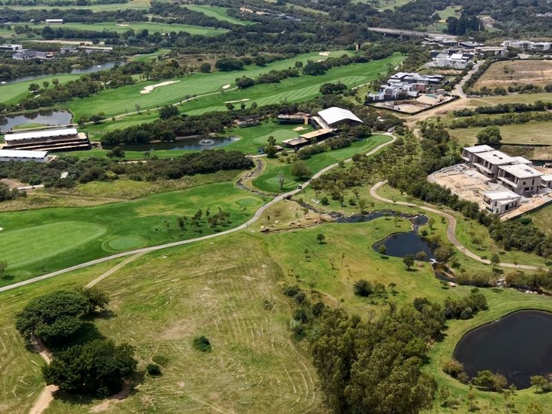 An expansive aerial view of a residential estate featuring a golf course, landscaped green spaces, and surrounding suburban development.