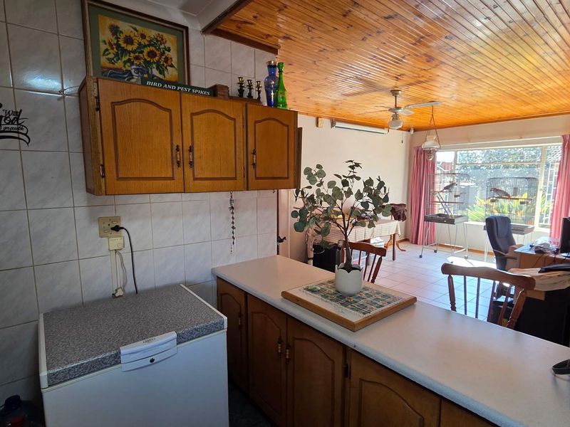 Open plan kitchen and living area featuring wooden cabinetry, tiled backsplash, and a distinctive wooden ceiling.