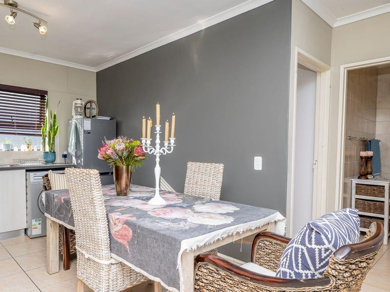 Open plan living and dining area featuring tiled flooring, neutral wall tones, and a compact kitchen corner with built-in cabinetry.