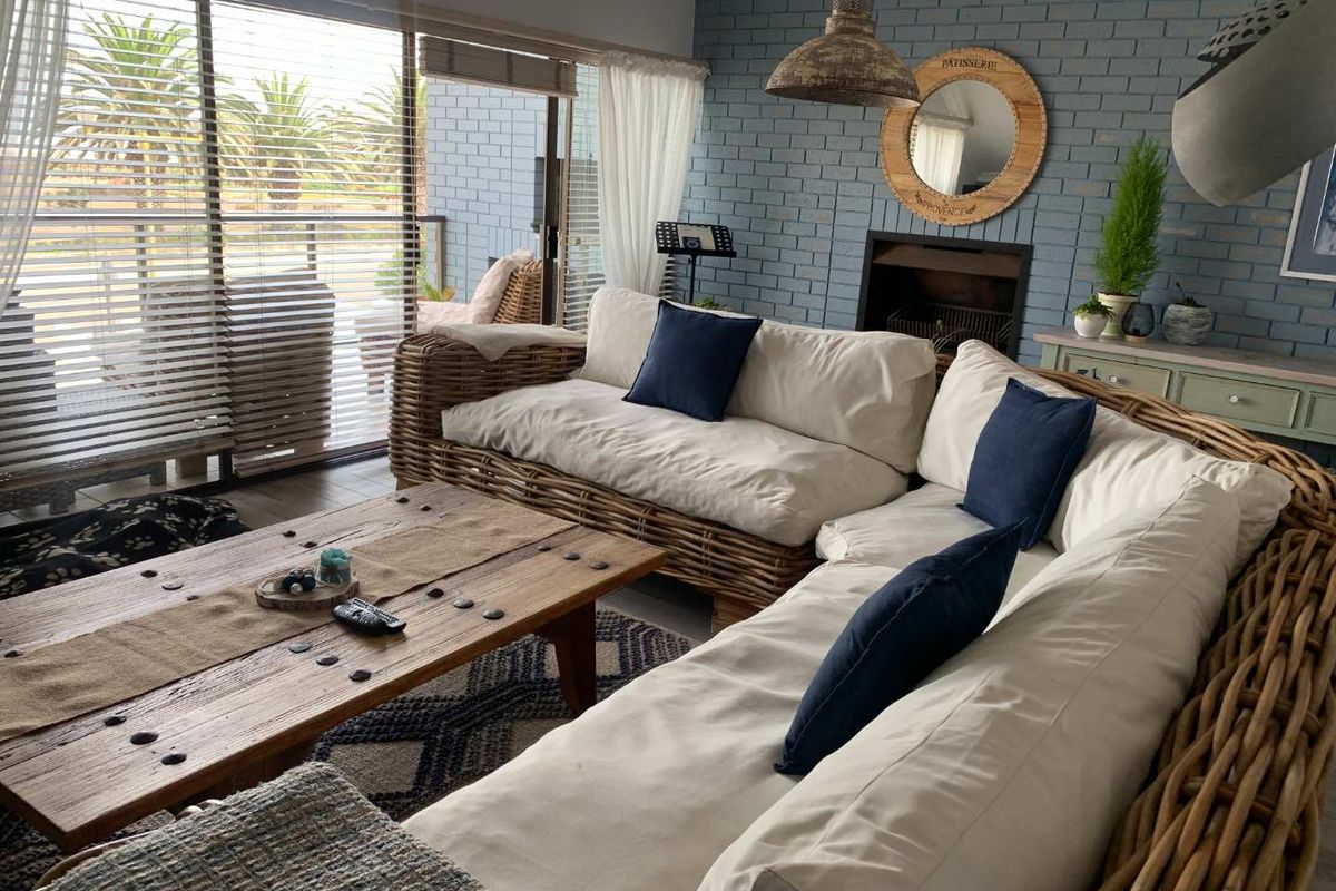 A cozy living room featuring a blue painted brick feature wall, a built-in fireplace, and large sliding glass doors leading to an outdoor patio area.