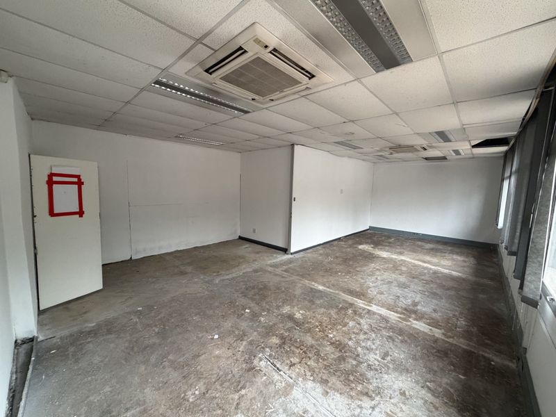 An empty industrial office space featuring a suspended ceiling with integrated air conditioning and lighting, requiring flooring and wall finishing.